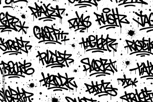 Graffiti style wall covered with various designs in black spray paint on a white background in an urban setting