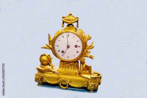 Antique mantel clock in golden color with symbols of science isolated on a light background. Items watches antiques technologies World tourism.