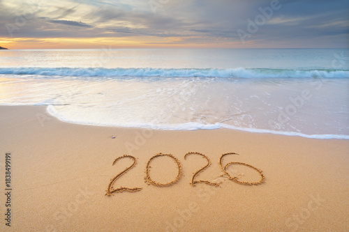 2026 year text symbol on the sea sand beach shore during sunset.