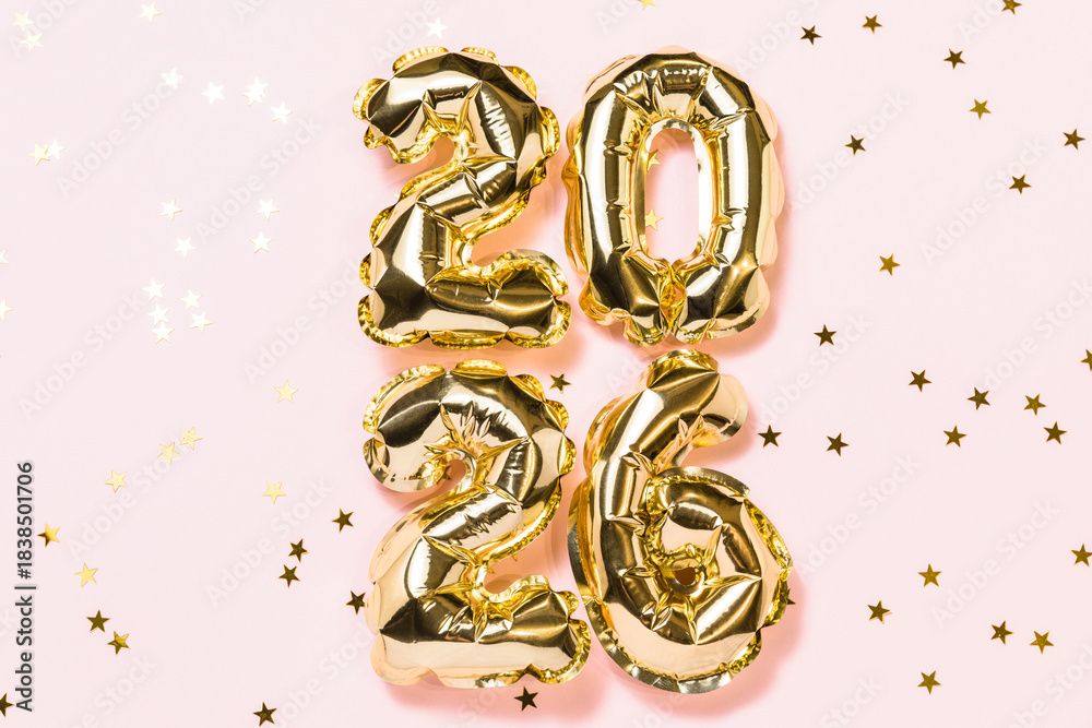 Fototapeta premium New year 2026 balloon celebration card. Gold foil helium balloons number 2026, party decoration, golden confetti stars on pink background. Flat lay, merry christmas banner, happy holidays concept.