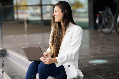 A young woman is working diligently on her laptop in a vibrant and modern urban setting