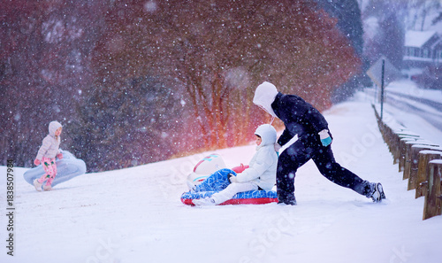 Happy Children Sledding Down a Snowy Hill – Winter Fun in Motion under Soft Falling Snow. Active Family Snow Day