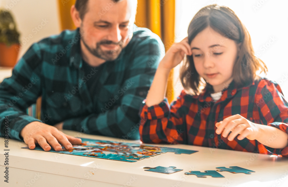 Fototapeta premium Father and daughter doing puzzle at home.
