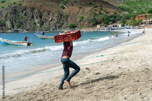 Un pescador lleva una caja con sardinas en la playa Manzanillo en la isla de Margarita.