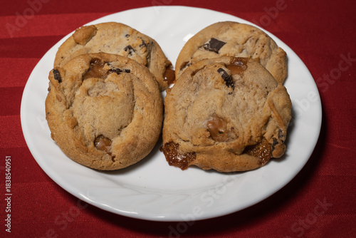 Cookies on white plate on red background (sea salt caramel chocolate chunk cookies)