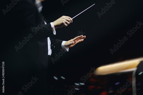 Foto Male conductor behind the podium directing orchestra on stage with pupitre, musi