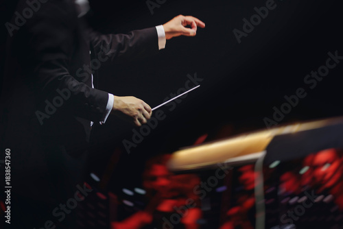 Tableau sur toile Male conductor behind the podium directing orchestra on stage with pupitre, musi