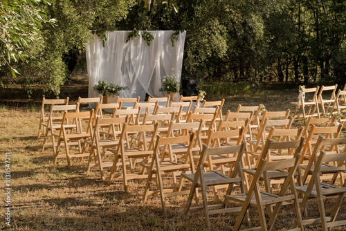 Outdoor wedding ceremony chairs with decorated arch in nature