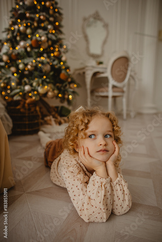 A charming 6-year-old blonde with curly hair in Christmas decorations 