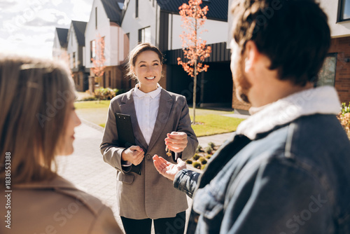 Foto Confident smiling real estate agent handing over keys to new homeowners