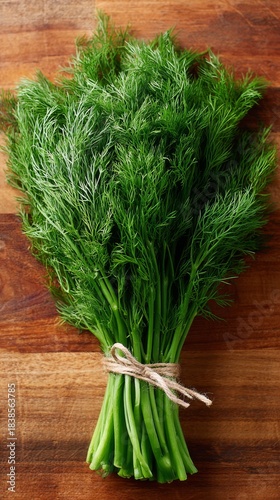 Fresh bunch of dill placed on wooden surface for cooking preparations in kitchen