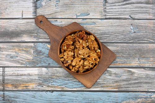 Peeled walnuts in wooden bowl isolated on wooden background. Top view.