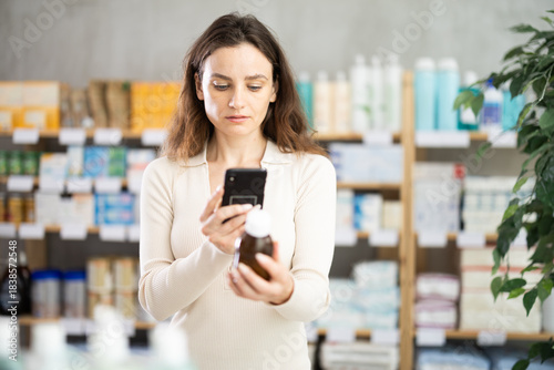 Adult woman buyer scanning qr code for medicinal syrup in pharmacy