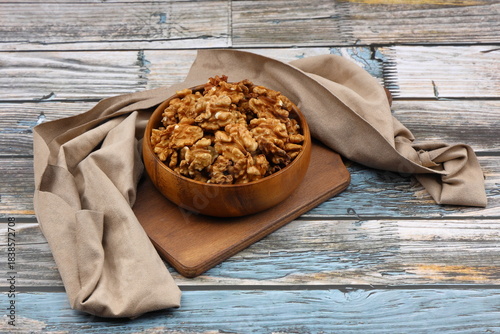 Peeled walnuts in wooden bowl isolated on wooden background. Top view.