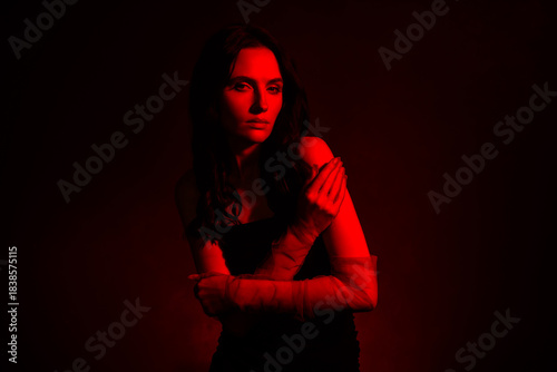 Elegant young brunette in red-illuminated studio lighting, showcasing fashion and feminine beauty inspiration
