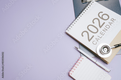 Business concept. 2026 calendar stethoscope pen notebook medical planning healthcare schedule workspace organization purple background office desk appointment reminder