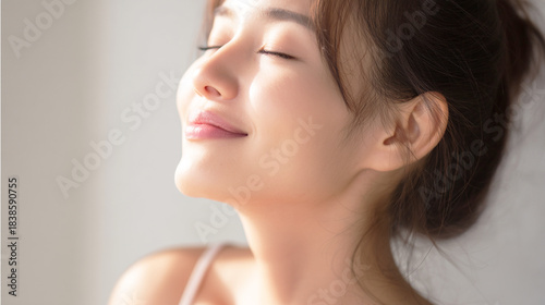 光の中で目を閉じて微笑む美しい女性の横顔
