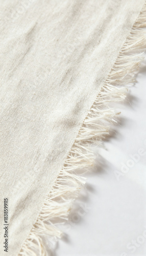 Close-up of linen fabric with frayed edge on white surface