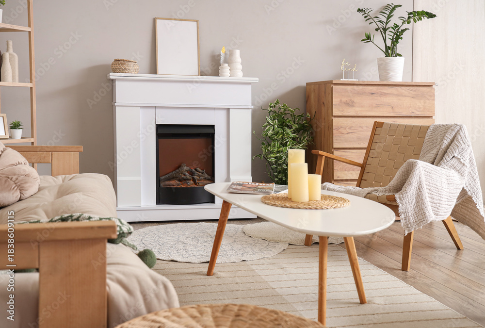 Fototapeta premium Fireplace, armchair and table in interior of light living room, closeup