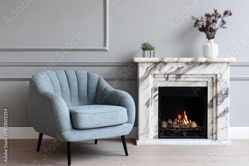 Elegant blue armchair sits beside a marble fireplace with a warm fire.