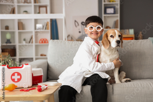Cute little doctor hugging Beagle dog on sofa at home