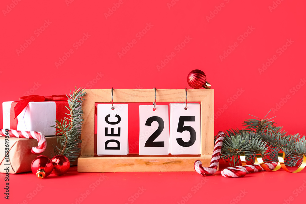Naklejka premium Gift boxes, decorations and calendar with date of Christmas on red background