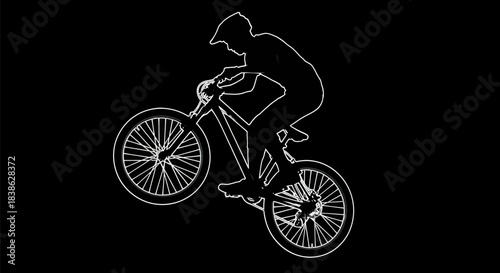 Silhouette of a cyclist performing a wheelie on a mountain bike.