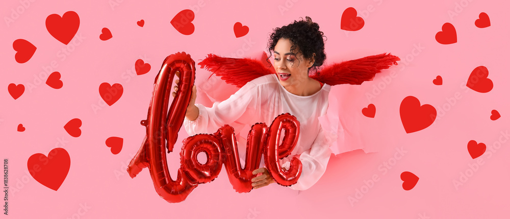 Obraz premium Young African-American woman dressed as Cupid with word LOVE visible through torn pink paper. Valentine's Day celebration