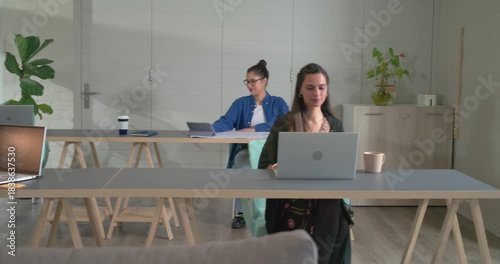 After Person1 shifting left, Indian woman in kurta typing on laptop holding coffee mug in office