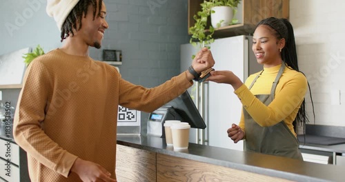 African American customer tapping smartwatch at cafe, barista scanning watch and handing cups