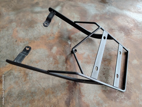 Unused motorcycle luggage carrier sitting on a rustic, distressed metal floor or table surface.