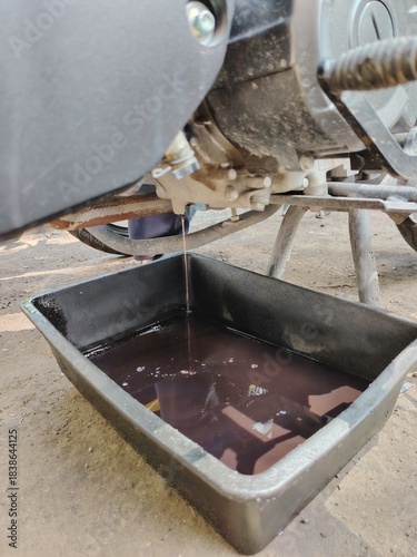 The messy process of draining old lubricant from a vehicle's engine at a workshop.