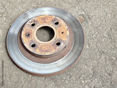 Rust and Metal: Old Vehicle Brake Rotor Resting on Rough Concrete Surface.