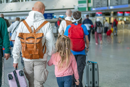 Travelers family with children, suitcases, and backpacks in airport terminal, ready for long-distance flight, air travel concept, checkin counter Airport Frankfurt am Main - October 3, 2025
