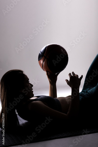 Silhouette of a young female basketball player holding a ball