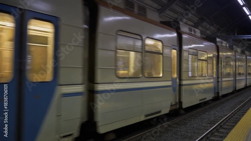 Dynamic blurred motion of an urban rapid transit train arriving or departing from a dimly lit underground subway station platform