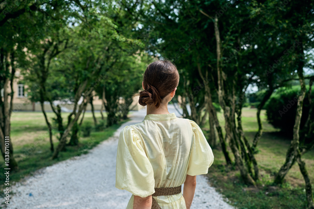 Fototapeta premium Woman dress walking back park pathway summer nature bun elegant authenticity inclusivity