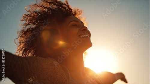 A joyful Black woman with curly hair, embracing the golden sunset with arms open wide, her silhouette backlit by sunlight flares, evoking the freedom and joy of Africa's Day of Freedom.