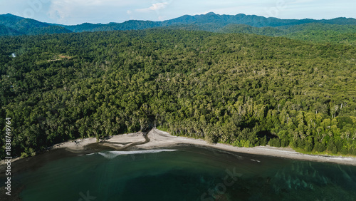 A calm coastal bay with a stream running out from the tropical forest.