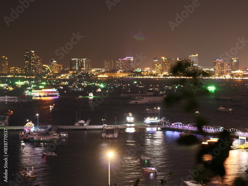 Fireworks lighting up the night sky in Pattaya, creating a vibrant and colorful display over the city and ocean. The bright explosions illuminate the coastline, capturing the festive atmosphere of thi