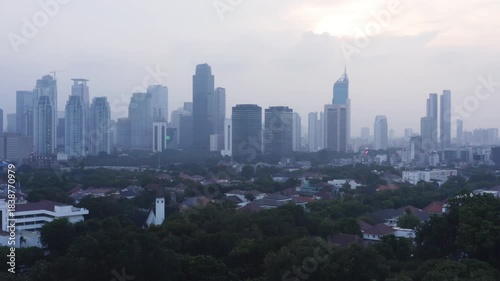 Dusk Drone Shot of Jakarta's Modern Skyscrapers and Lush Residential Area with Hazy Sky