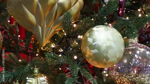 Christmas tree decorations and balls hang on the tree.