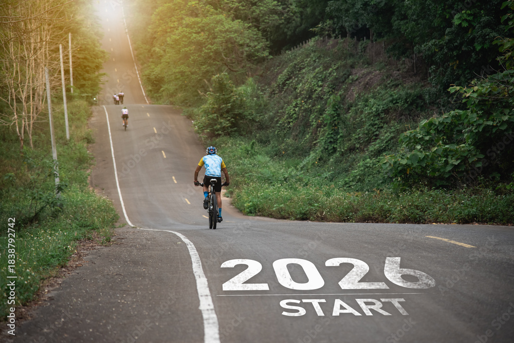 Naklejka premium New Year 2026. Cyclist Riding Up a Scenic Mountain Road with a 2026 Start Sign Symbolizing New Beginnings and Adventure in Nature