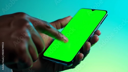 Close-up of a person's hand using a smartphone with a green screen display for custom content