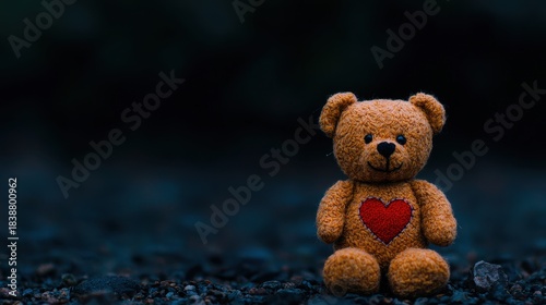 Cute teddy bear with heart on chest in a dark outdoor setting, soft and cuddly