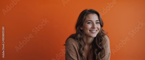 Young woman smiling in front of vibrant orange background