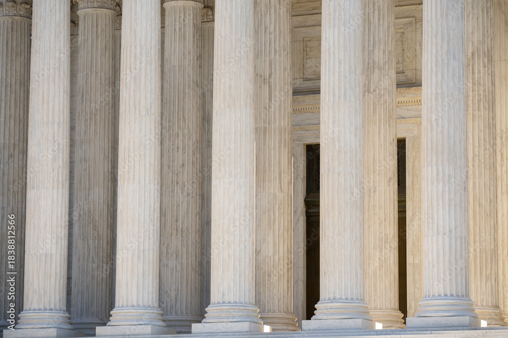 Naklejka premium Classical architecture defining monumental columns. Historic government architecture with marble pillars. White stone columns shaping civic architecture. Court house exterior with classical design.