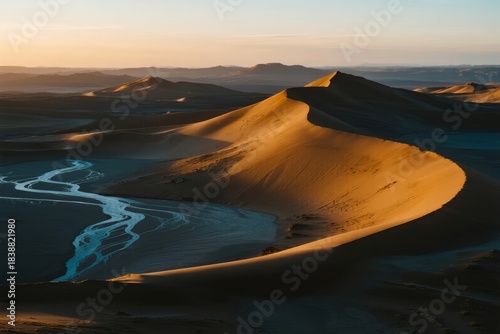 Fototapeta Naklejka Na Ścianę i Meble -  Golden sand dunes at sunset with a winding river in a desert landscape