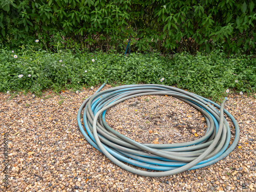 Garden Hose on Gravel Path in Outdoor Restaurant Garden.