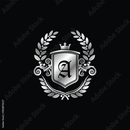 Classic silver heraldic crest featuring ornate shield with crown, initial A, and elegant laurel wreath design.
